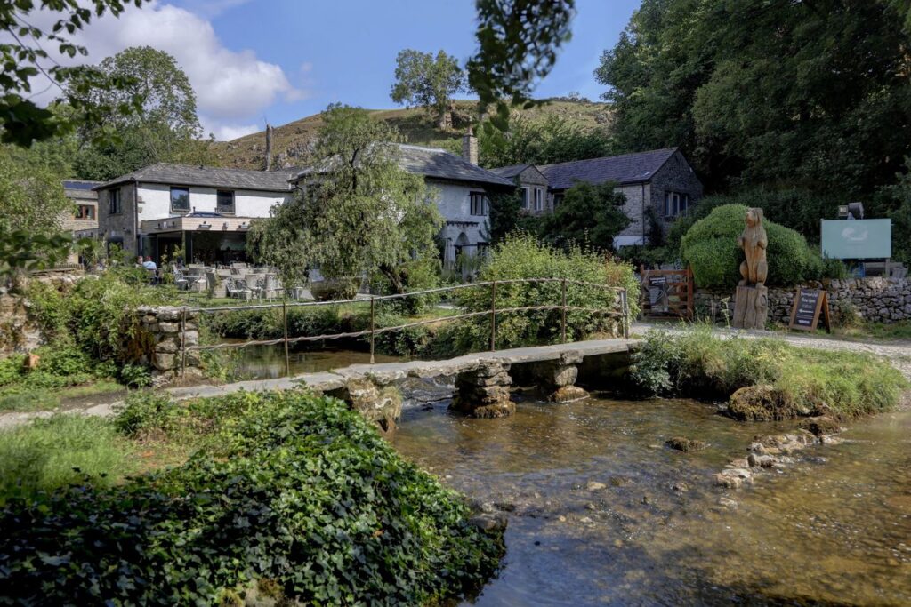 Beck Hall in the Yorkshire Dales with a stream and stone footbridge in the foreground